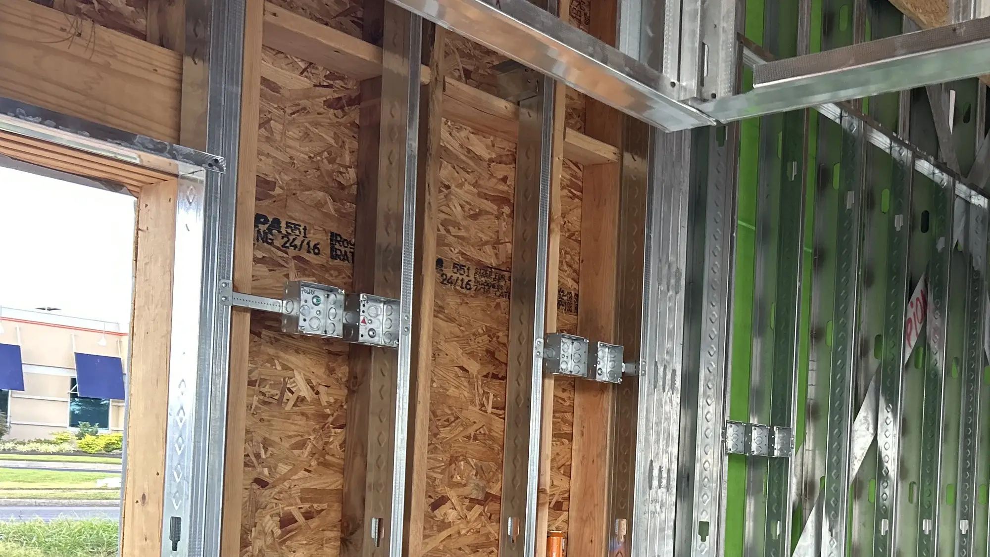 Device boxes mounted on steel studs during rough-in, with the framing open