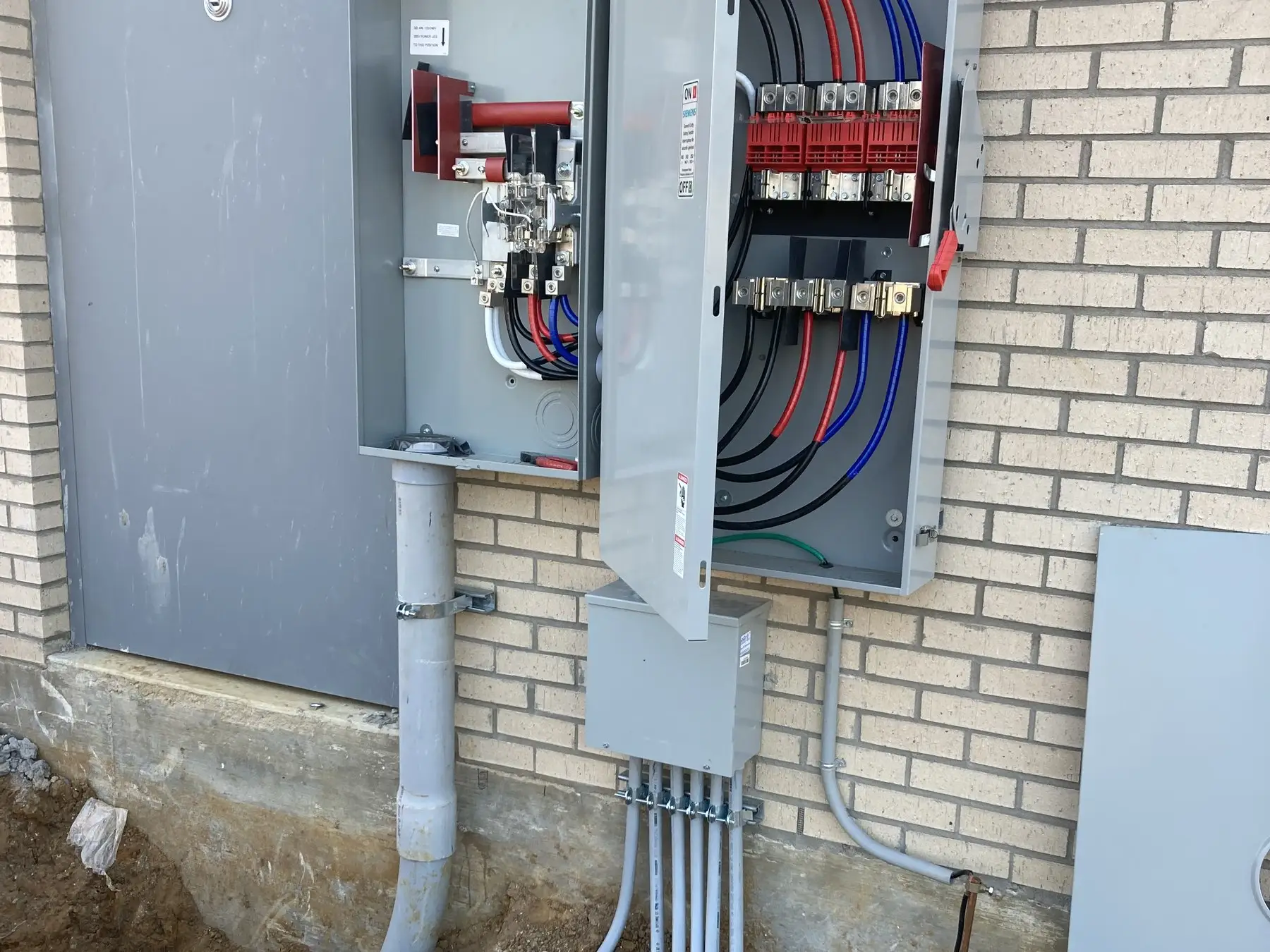 An exterior service panel with conduit dropping into the ground